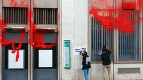 Des militants d'Action Justice Climat collent des pancartes après avoir peint la façade de la multinationale bancaire et holding de services financiers française BNP Paribas, Place de la Bourse à Paris, le 24 octobre 2024, alors qu'ils accusaient BNP Paribas de financer l'État israélien, par l'achat d'obligations, et de participer ainsi à la guerre à Gaza.