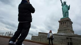Des touristes devant la statue de la Liberté, à New York