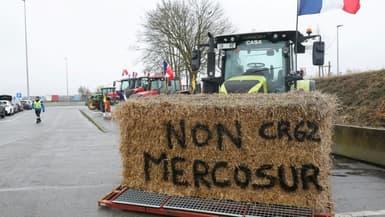 Une botte de foin "Non au Mercosur" sur un tracteur alors que des agriculteurs participent à un blocage sur l'autoroute A1 près de Fresnes-lès-Montauban, le 12 janvier 2026 dans le Pas-de-Calais