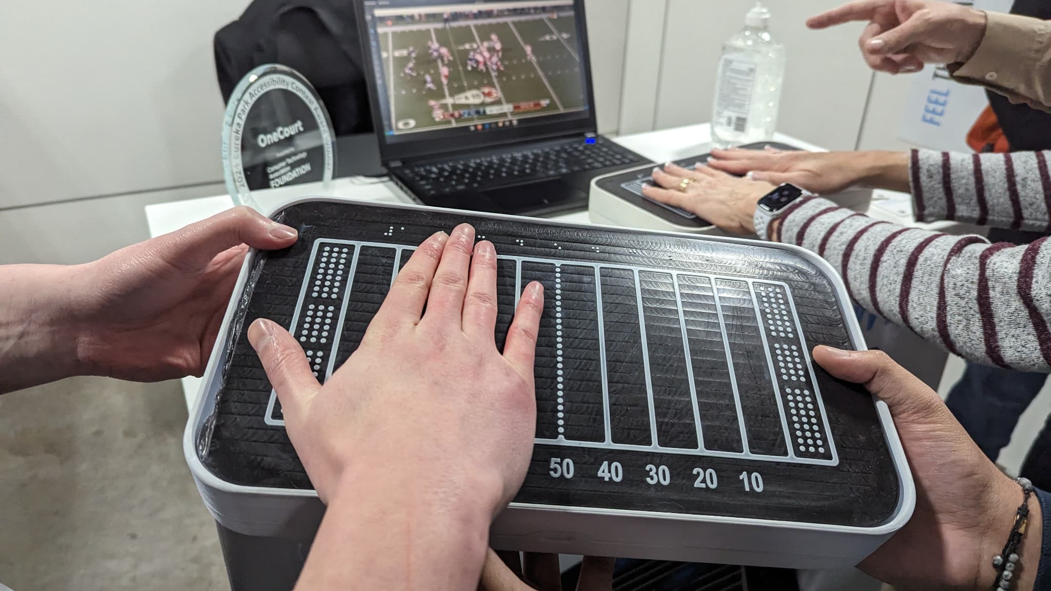 Avec la tablette OneCourt, les personnes aveugles peuvent suivre un match de football américain, de tennis ou de hockey grâce à des vibrations dans leurs mains. Avec la tablette OneCourt, les personnes aveugles peuvent suivre un match de football américain, de tennis ou de hockey grâce à des vibrations dans leurs mains.
