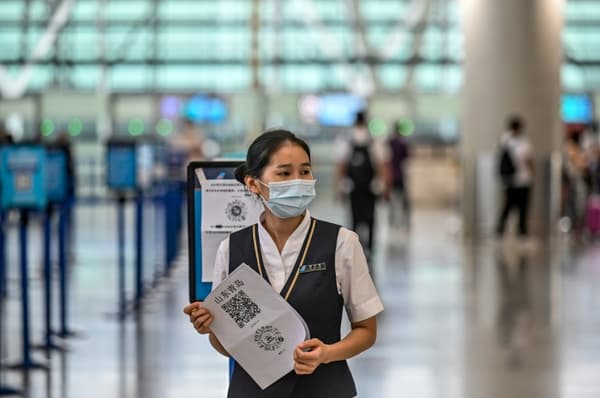 Une employée de l'aéroport de Shanghai-Pudong tient un QR code pour vérifier l'état de santé des voyageurs, le 11 juin 2020 en Chine Une employée de l'aéroport de Shanghai-Pudong tient un QR code pour vérifier l'état de santé des voyageurs, le 11 juin 2020 en Chine