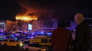 Deux personnes regardent le Crocus City Hall en flammes, à Krasnogorsk, près de Moscou, en Russie, le 22 mars 2024