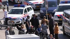 Policier établissant un périmètre de sécurité autour d'un centre commercial de la ville d'Alphen aan den Rijn, dans l'ouest des Pays-Bas, où une fusillade a fait six morts et au moins 13 blessés samedi. /Photo prise le 9 avril 2011/REUTERS/HDC MEDIA/Hedsk