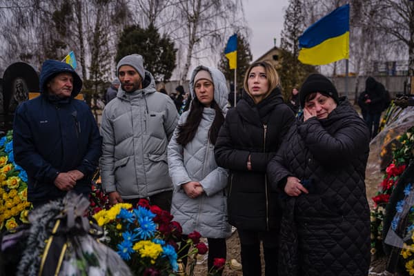Des habitants de Boutcha se recueillent devant les tombes de leurs proches, un an après le début de l'offensive russe, le 24 février 2023