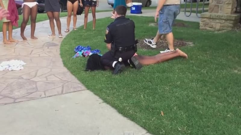 Le policier en train de plaquer au sol une adolescente en maillot de bain.