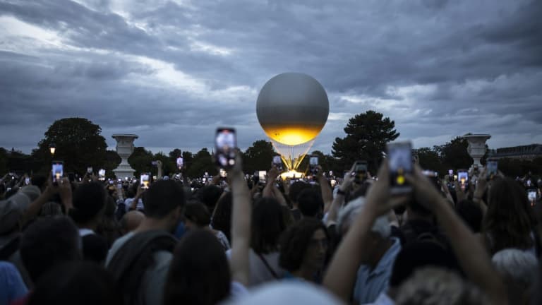 Des visiteurs photographient la vasque des Jeux olympiques et paralympiques de Paris 2024 au coucher du soleil, dans le Jardin des Tuileries, à Paris, le 7 août 2024 (image d'illustration).