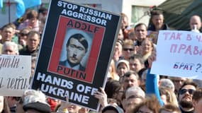 Sur une pancarte un portrait compare Poutine à Hitler lors d'une manifestation hostile à l'annexion de la Crimée par la Russie, à Kiev le 23 mars 2014.