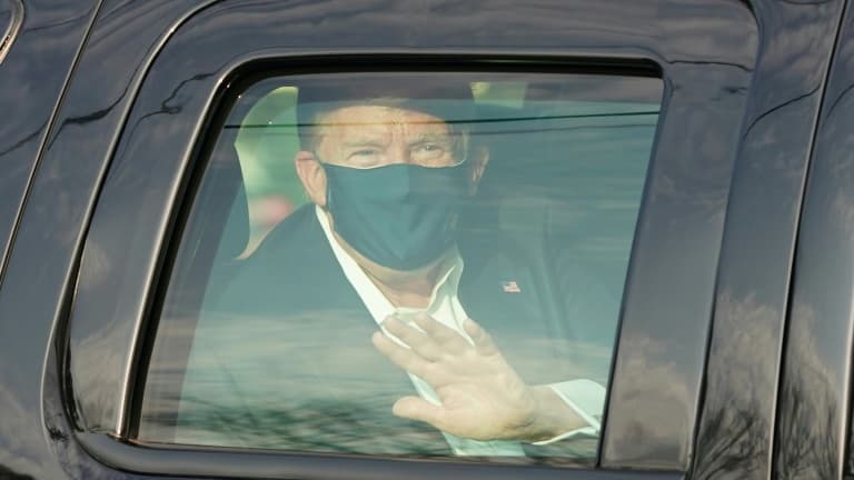 Le président américain Donald Trump salue ses symathisants depuis la limousine présidentielle lors d'une brève sortie de l'hôpital militaire de Walter Reed à Bethesda, près de Washington, le 4 octobre 2020                    