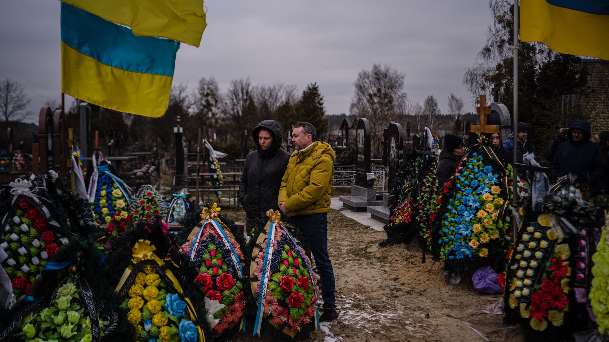 Des Ukrainiens se recueillent devant les tombes de leurs proches devant l'église Saint-André à Boutcha, un an après le début de l'offensive russe, le 24 février 2023 Des Ukrainiens se recueillent devant les tombes de leurs proches devant l'église Saint-André à Boutcha, un an après le début de l'offensive russe, le 24 février 2023