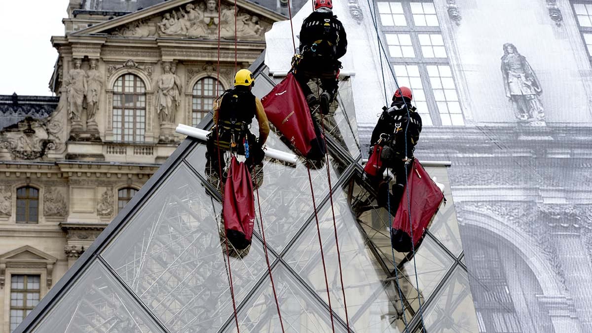 Des alpinistes ont installé le collage de JR sur le verre de le pyramide du Louvre le 24 mai.