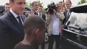 Emmanuel Macron en train de présenter son Peugeot 5008 présidentiel à un jeune garçon.