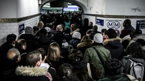 Des usagers des transports en commun font la queue pour accéder au quai de la ligne 1 du métro parisien lors d'une grève des transports à la SNCF et à la RATP, le 12 décembre 2019 à Paris