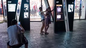 Deux amies s'amusent à prendre une pose lascive devant le magasin Uniqlo incriminé, à Pékin, le 15 juillet 2015.