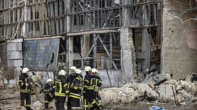 Des pompiers sont assis au milieu de débris dans la zone d'un institut de recherche, qui fait partie de l'Académie nationale des sciences d'Ukraine, après une frappe de drones qui a fait au moins un mort, dans le nord-ouest de Kiev, le 22 mars 2022