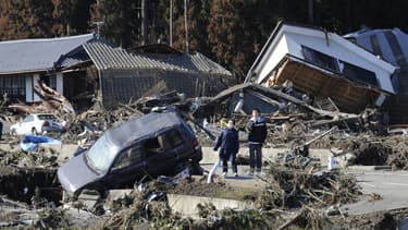 Des piétons se tiennent à côté de maisons effondrées après avoir été frappés par un tsunami à Minamisoma, préfecture de Fukushima, le 12 mars 2011. (Photo d'illustration)