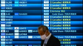 Un homme passe devant un écran montrant les vols annulés à l'arrivée de l'aéroport Haneda de Tokyo, au Japon, à cause du variant Omicron du coronavirus, le 30 novembre 2021