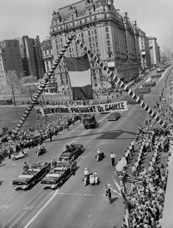 Le général de Gaulle, en voyage officiel aux Etat-Unis, traverse, le 22 avril 1960, debout dans une voiture aux côtés du président américain Dwight Eisenhower, une large avenue de Washington sous un arc de triomphe et une banderole de bienvenue au président de Gaulle.