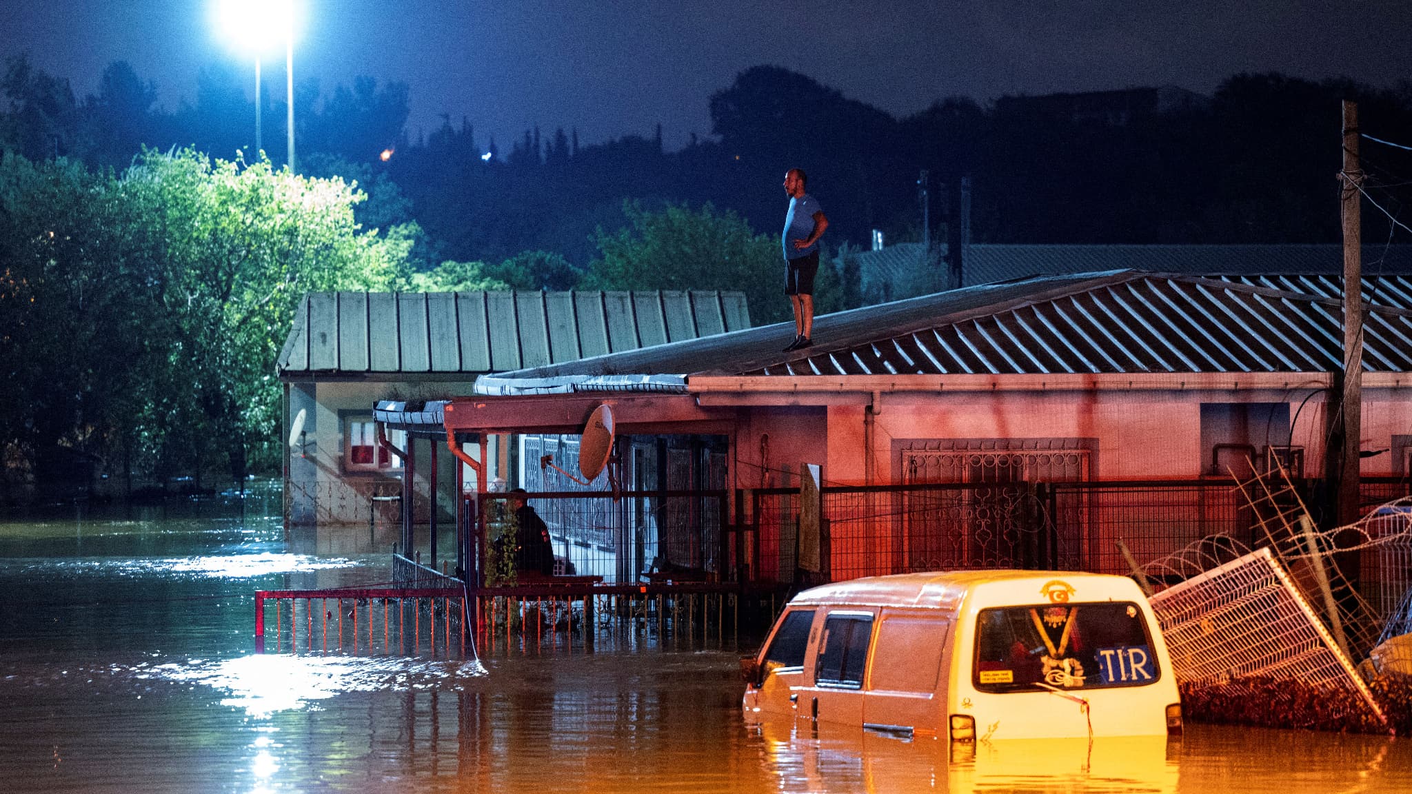 Un homme se tient sur un toit en attendant d'être secouru par un bateau lors des inondations dans le district de Kucukcekmece à Istanbul le 5 septembre 2023.