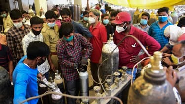 Des gens remplissent des bouteilles d'oxygène médical pour les patients atteints du coronavirus Covid-19 dans une station de remplissage d'oxygène à Allahabad (Inde) le 20 avril 2021.