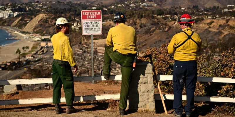 Des pompiers observent les montagnes brûlées de Santa Monica depuis le quartier de Pacific Palisades à Los Angeles, en Californie, le 13 janvier 2025.