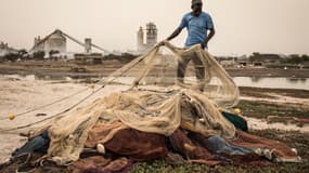 Un pêcheur trie ses filets devant la cimenterie SOCOCIM, le long du littoral à Bargny, au Sénégal, le 16 juin 2020.