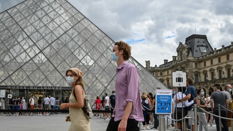 Des touristes passent devant la Pyramide du Louvre conçue par l'architecte Ieoh Ming Pei, le 15 août 2020 à Paris