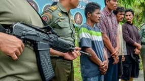 Des policiers escortent quatre hommes suspectés d'avoir tué et mangé des ours malais, le 3 avril 2018 à Kerta TunasJaya, en Indonésie