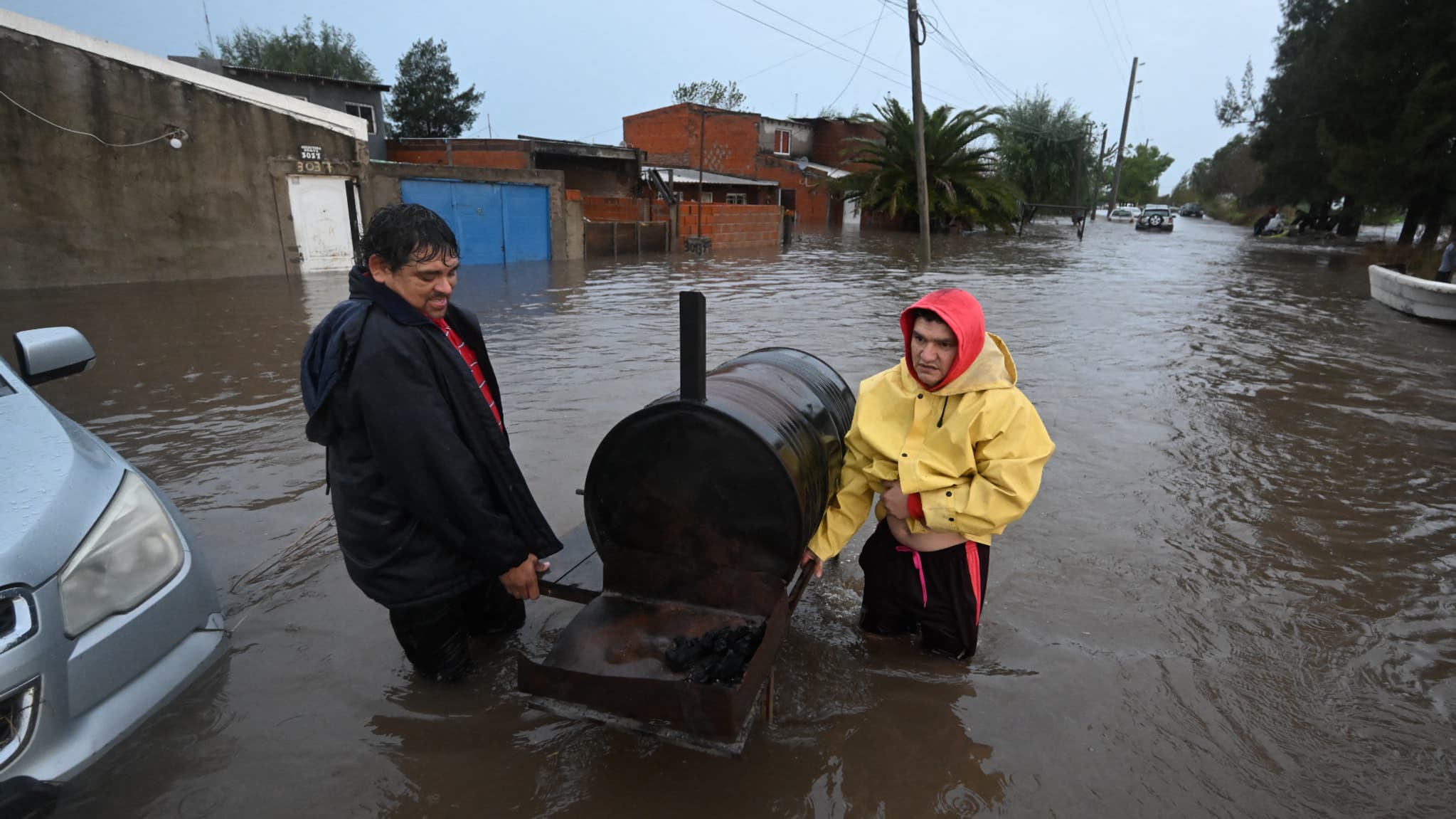 Des hommes déplacent un gril le long d'une rue inondée après de fortes pluies à Campana, dans la province de Buenos Aires, le 17 mai 2025.