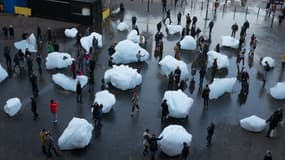 Des passants interagissent avec les blocs de glace d'une exposition intitulée "Ice Watch" créée par l'artiste dano-islandais Olafur Eliasson et le géologue groenlandais Minik Rosing, à Londres le 11 décembre 2018. 