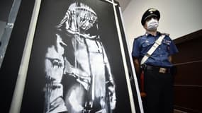 Un policier italien à côté de l'oeuvre de Banksy, volée au Bataclan en 2019, et retrouvée en Italie, lors d'une conférence de presse, le 11 juin 2020 à l'Aquila
