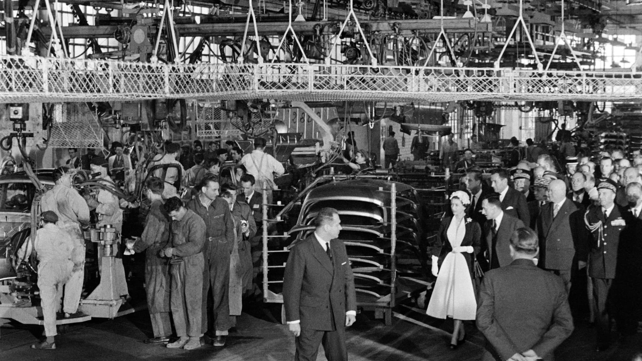 Queen Elizabeth II flanked by French carmaker Renault CEO Pierre Dreyfus visits the Renault car factory in Flins during a state visit in France on April 10, 1957.