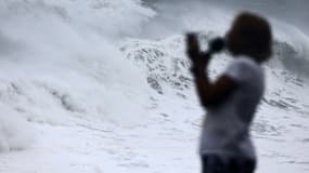 Une personne devant une grande vague sur la plage de Saint-Benoit, à La Réunion, avant le passage du cyclone Emnati, le 20 février 2022