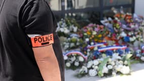 Un policier se recueille devant les fleurs déposées en hommage à Éric Masson, dimanche 9 mai 2021, devant son commissariat d'Avignon