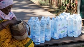 Une femme est assise à côté de packs de bouteilles d'eau reçus lors d'une distribution, le 21 septembre 2023 à Mayotte