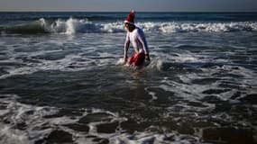 Un homme portant un chapeau de Père Noël prend son premier bain de l'année lors des célébrations du Nouvel An sur la plage de Carcavelos à Oeiras, dans la banlieue de Lisbonne, le 1er janvier 2024.