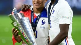 L'attaquant français Kylian Mbappé (g) et le milieu de terrain français Paul Pogba posent avec le trophée à la fin de la finale de la Ligue des Nations de football entre l'Espagne et la France au stade San Siro de Milan, le 10 octobre 2021.