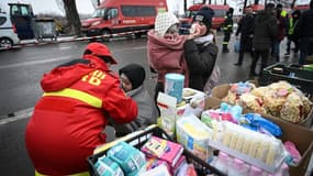 Un employé roumain des services d'urgence enveloppe d'une couverture un enfant venu d'Ukraine, à Siret en Roumanie le 2 mars 2022