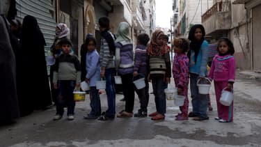Des enfants attendent de recevoir des rations de nourriture, dans la banlieue d'Alep, en Syrie, en novembre 2014.