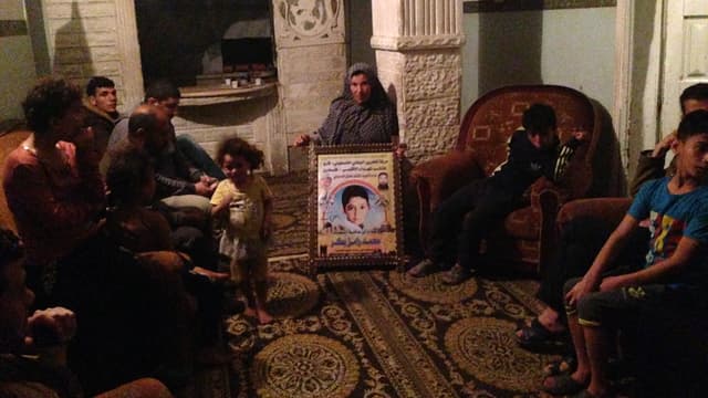 La famille Bakr dans son salon avec la mère et le portrait de Zacharia dans les mains 
