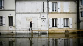 Une femme marche sur un pont de bois intallé dans les rues inondées de Saintes (Charente), le 15 décembre 2023