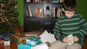 Un jeune garçon en train d'ouvrir ses cadeaux le matin de Noël.