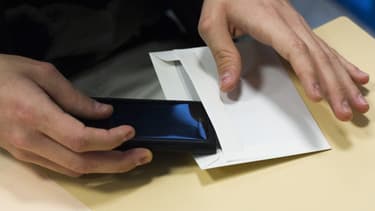 Un lycéen range son portable dans une enveloppe avant l'épreuve de philosophie du bac, le 17 juin 2013 à Paris.