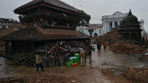 Des Népalais passent près de bâtiments endommagés par le tremblement de terre sur la place Durbar à Katmandou le 30 avril 2015