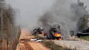 Des véhicules militaires israéliens brûlent après une attaque près de la fontière israélo-libanaise.