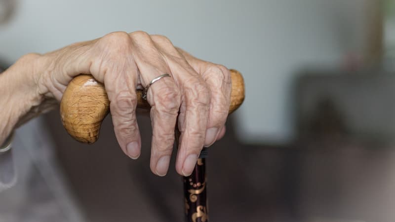 Main d'une personne âgée tenant une canne. (photo d'illustration)