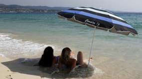 Deux femmes, allongées sur le sable, à l'ombre d'un parasol, sur la plage d'Ajaccio, en Corse
