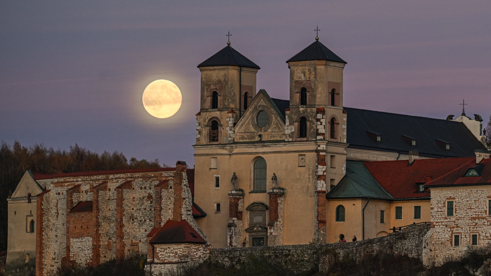 Суперлуна восходит за многовековым бенедиктинским аббатством 5 ноября 2025 года в Кракове, Польша.