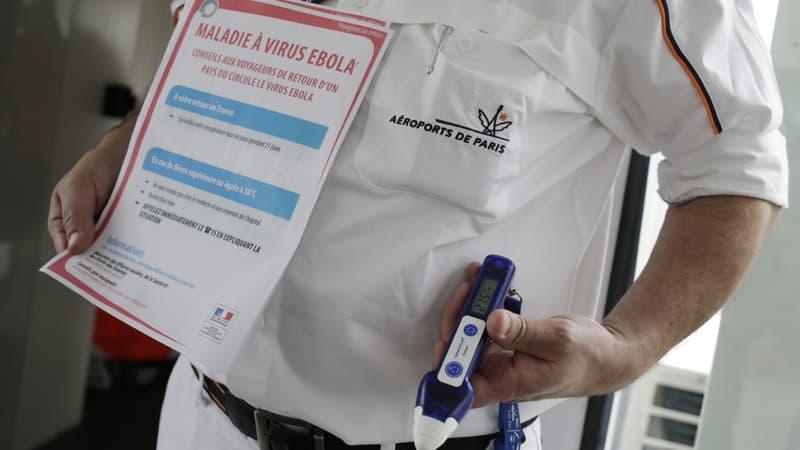 Un employé des urgences médicales des aéroports de Paris tient une note d'information sur le virus Ebola ainsi qu'un thermomètre