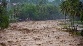 Des personnes restent sur les berges de la rivière pendant les inondations à Padang, dans la province de Sumatra occidental, le 27 novembre 2025. 