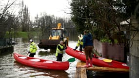 Des employés municipaux prêtent un kayak à une habitante pour lui permettre de circuler dans son jardin et à l'extérieur de sa résidence alors que la Charente est en crue dans la ville de Cognac, le 15 décembre 2023.